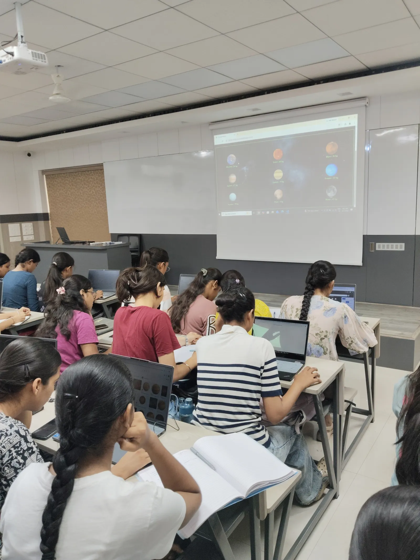 Students following along on laptops during a class at Info Planet